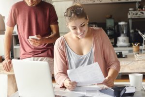 a woman smiling at her monthly statement from a personal money market account